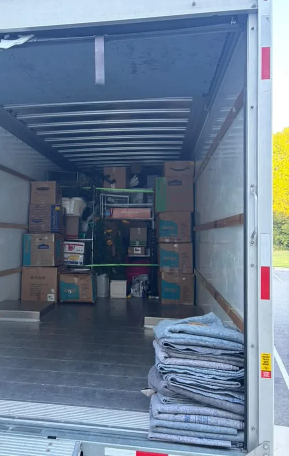 Interior de un camión alquilado con cajas apiladas y mantas de mudanza dobladas
