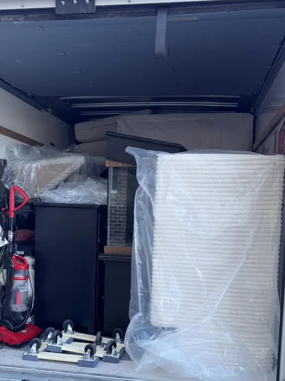 Muebles envueltos en plástico junto a plataformas con ruedas dentro de un camión