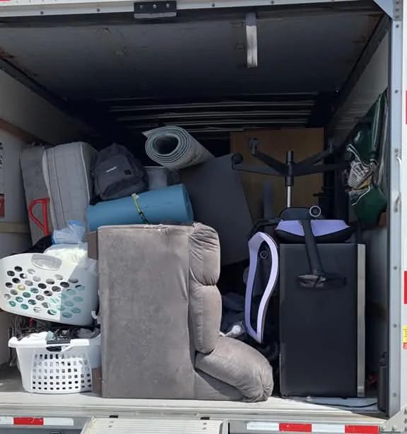 Sillón reclinable, silla de oficina y artículos del hogar acomodados en la caja de un camión